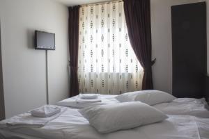 弗洛雷什蒂Pensiunea Vidcom的一张带白色床单和枕头的床,位于窗户前