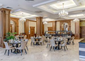 阿特劳苏丹皇宫酒店的用餐室配有桌椅和吊灯。