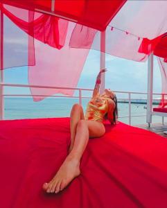 敖德萨Club House Arkadia Beach的躺在雨伞下的红色床上的妇女
