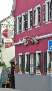 Osthofen维本罗斯葡萄酒旅馆的一座红色的建筑,上面有黑色百叶窗和植物