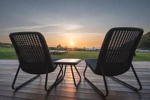 韦加港Hotel Rural La Sobreisla的两把椅子坐在甲板上,欣赏日落美景