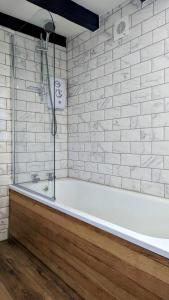 库姆马丁Yetland Farm Holiday Cottages的白色的浴室设有浴缸和白色砖墙