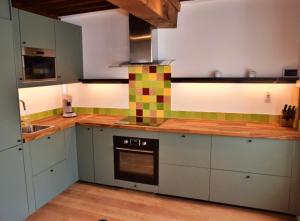 沃克莱Chez Daniel的厨房配有绿色和白色的橱柜和炉灶。
