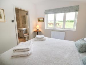 切尔滕纳姆Flagstone Cottage的卧室配有白色床和毛巾