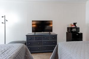 马吉谷Heart of the Valley Motel的一间卧室配有两张床和一个带电视的梳妆台。
