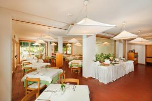 圣多米诺凯里伊索莱特雷米蒂酒店的餐厅设有白色的桌椅和白色的桌子。