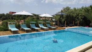 卡皮塔纳villa Orchidee Sardegna的一个带蓝色椅子和遮阳伞的游泳池