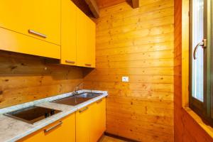 Capanne di SillanoVillaggio Anemone - Chalet Anemone的厨房配有黄色橱柜和水槽