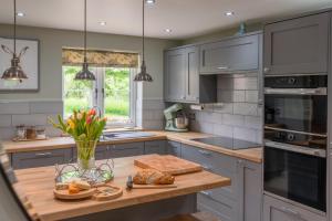 AldertonOrchard Cottage的厨房配有灰色的橱柜和木制台面