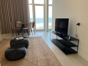 科武港Porto Covo Praia Hotel & SPA的客厅配有电视和桌椅