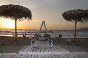 科斯镇Pelagos Suites Hotel & Spa的海滩上的长凳,配有两把遮阳伞