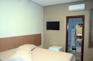 邦热苏斯-达拉帕Hotel Grutta的卧室配有一张床,墙上配有电视