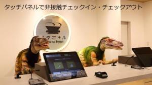 金泽Henn na Hotel Kanazawa Korimbo的两座恐龙雕像,坐在一张桌子旁,配有一台笔记本电脑