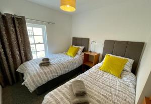 布里德波特The Knots-Spacious 3 bedroom apartment in Bridport的一间卧室配有两张带黄色枕头的床和窗户。