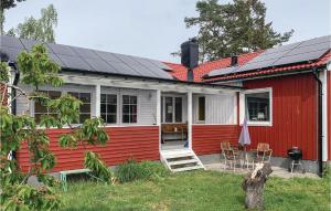 BromöllaAmazing Home In Bromlla With 3 Bedrooms, Sauna And Wifi的一座红白色房子,上面有太阳能电池板