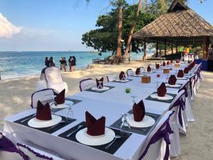 丹戎槟榔Madu Tiga Beach and Resort的海滩上一排带帽子的桌子