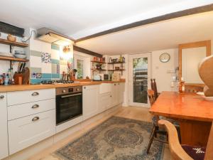 汤顿Teacher's Cottage的厨房配有白色橱柜和木桌