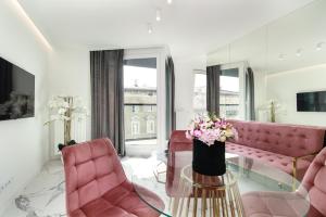 波兹南Apartamenty HashtagWilda_Apartament Złoty的客厅配有粉色家具和鲜花玻璃桌