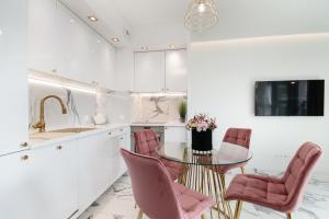 波兹南Apartamenty HashtagWilda_Apartament Złoty的厨房配有玻璃桌和粉红色的椅子