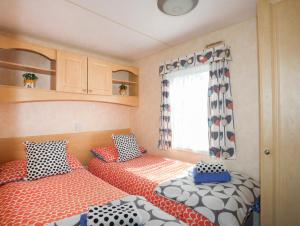 霍利黑德Trewan Chalet的一间大篷车卧室,配有两张床和窗户