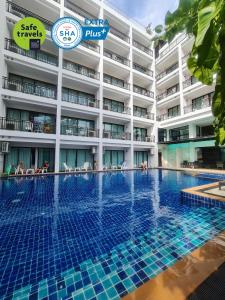 芭东海滩Paripas Patong Resort - SHA Extra Plus的大楼前的酒店游泳池