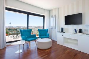 马德里马德里本塔斯NH酒店的客厅配有2把蓝色椅子和电视