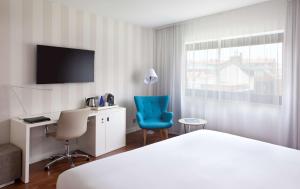 马德里马德里本塔斯NH酒店的酒店客房设有一张床、一张书桌和一台电视机。