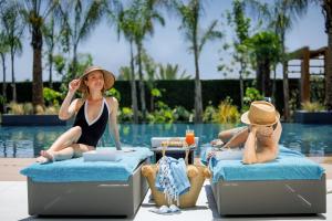 阿依纳帕Amanti, MadeForTwo Hotels - Ayia Napa的两名女性坐在游泳池畔的床上