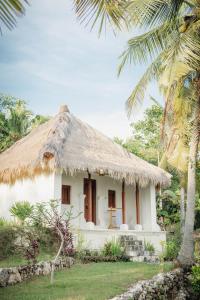 ToyapakehUmah Ilu Island Retreat Penida的白色的小房子,带有茅草屋顶