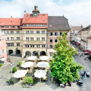 康斯坦茨Romantik Hotel Barbarossa的前面有白色雨伞的大建筑