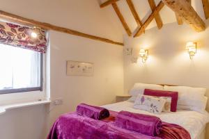 迪斯Garden Cottage的一间卧室配有一张带紫色床单的床和窗户。