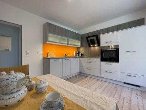 特希尔Marions Apartments Greetsiel的厨房配有白色橱柜和木桌