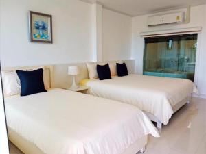格兰岛Koh Larn Riviera的配有白色床单和蓝色枕头的客房内的两张床