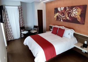 加拉加斯Novo Hotel的一间卧室配有一张带红色和白色枕头的大床