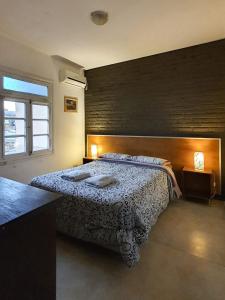 布宜诺斯艾利斯卡洛斯葛戴尔旅馆的一间卧室设有一张床和砖墙
