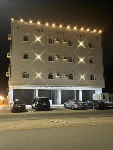Al Qunfudhahشقق الشاطئ的一座白色的大建筑,前面有汽车停放