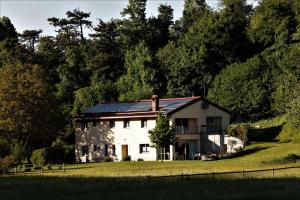 SenožečeGUESTHOUSE Idila pod Nanosom的一座白色的房子,在田野上设有太阳能屋顶