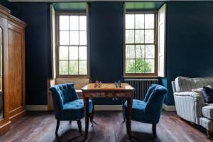 欧克希尔Topside House - Beautiful 7 bedroom house with hottub wifi and parking near Bath Wells Frome的一间拥有蓝色墙壁和桌椅的房间
