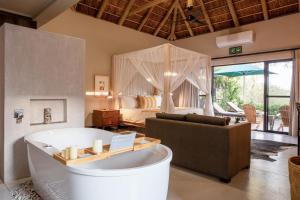 侯斯普瑞特Moya Safari Lodge & Villa的一间带浴缸的客厅和一间卧室