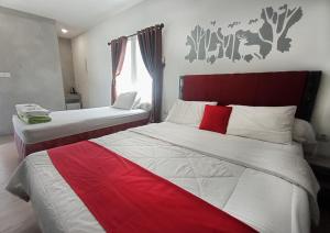 班达楠榜RUMAH KOPI SYARIAH HOTEL的一间卧室配有两张红色和白色床单