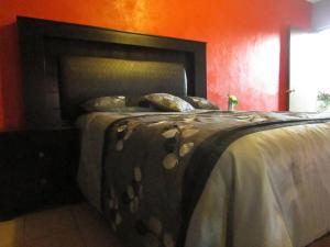 San CarlosHotel Isabela的红色客房内的一张床位,配有床罩和枕头