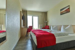 萨斯尼茨Rügen-Hotel的酒店客房设有一张带红色毯子的大床