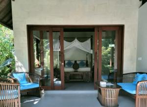 乌布毕思马别墅酒店的庭院配有椅子和一张带天蓬的床。
