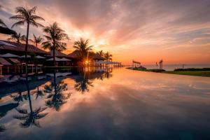 金兰The Anam Cam Ranh的棕榈树游泳池的日落