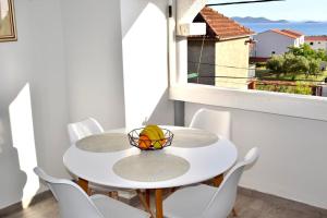 帕科坦Apartments Petar Maksan的一张带椅子的白色桌子和一碗水果