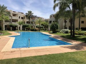RodaRODA Golf & Beach Resort Wonderful Ground Floor Apartment的棕榈树和建筑度假村内的游泳池