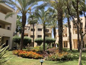 RodaRODA Golf & Beach Resort Wonderful Ground Floor Apartment的一座公园,在一座建筑前有棕榈树和鲜花
