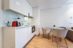 波尔图Antas Park Apartment的厨房配有白色橱柜和桌椅