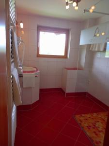 拉姆绍达赫斯坦Landhaus Wieser的浴室铺有红色瓷砖地板,设有窗户。