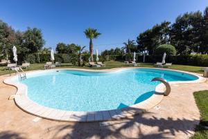 圣维托诺曼Villa Mamma Grazia Rooms的庭院内的游泳池,带椅子和树木